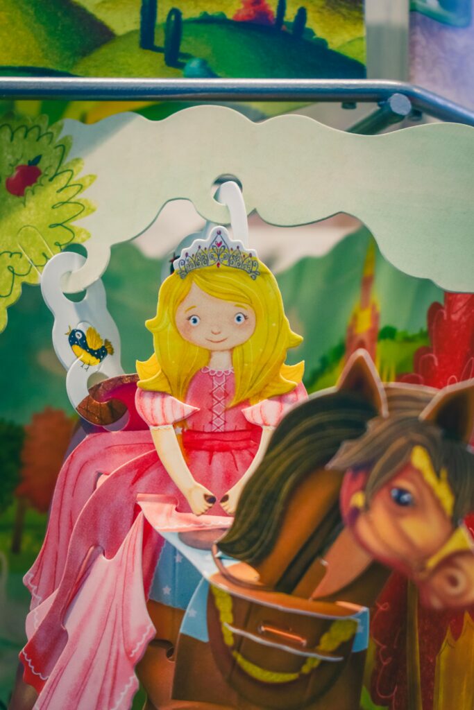 Whimsical paper cutout of a cartoon princess on a horse, set in a fantasy landscape.