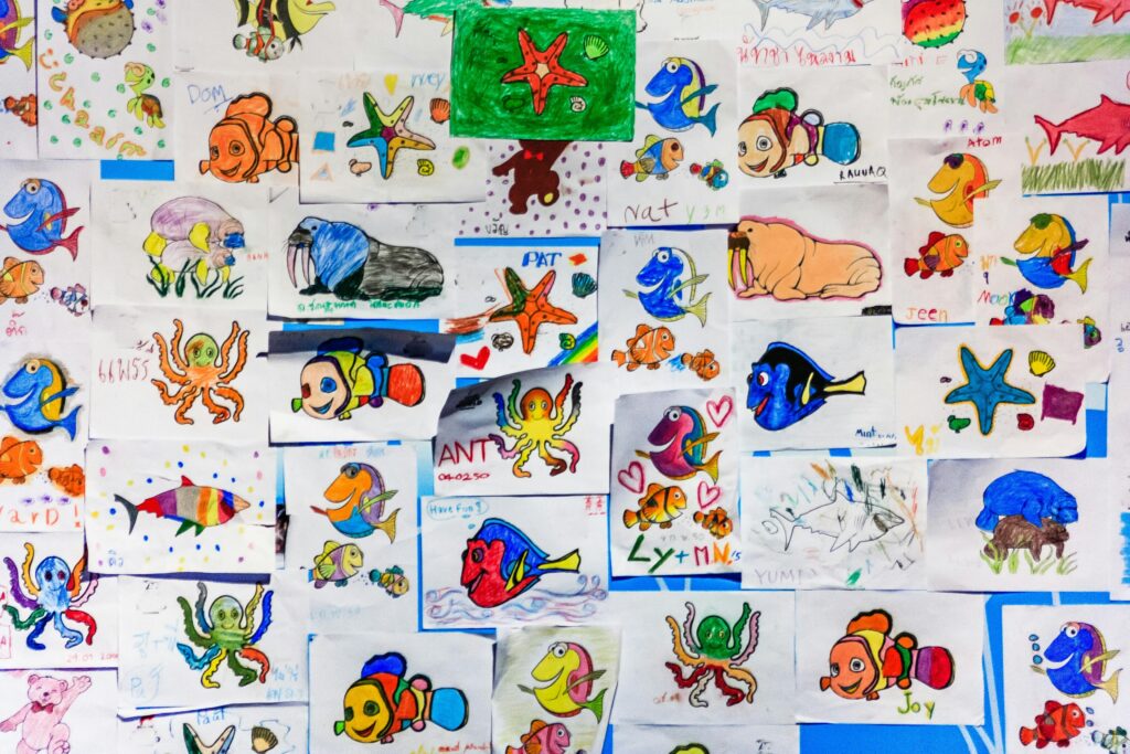 A colorful collage of children's drawings featuring various marine life in vibrant hues.