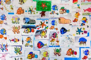 A colorful collage of children's drawings featuring various marine life in vibrant hues.